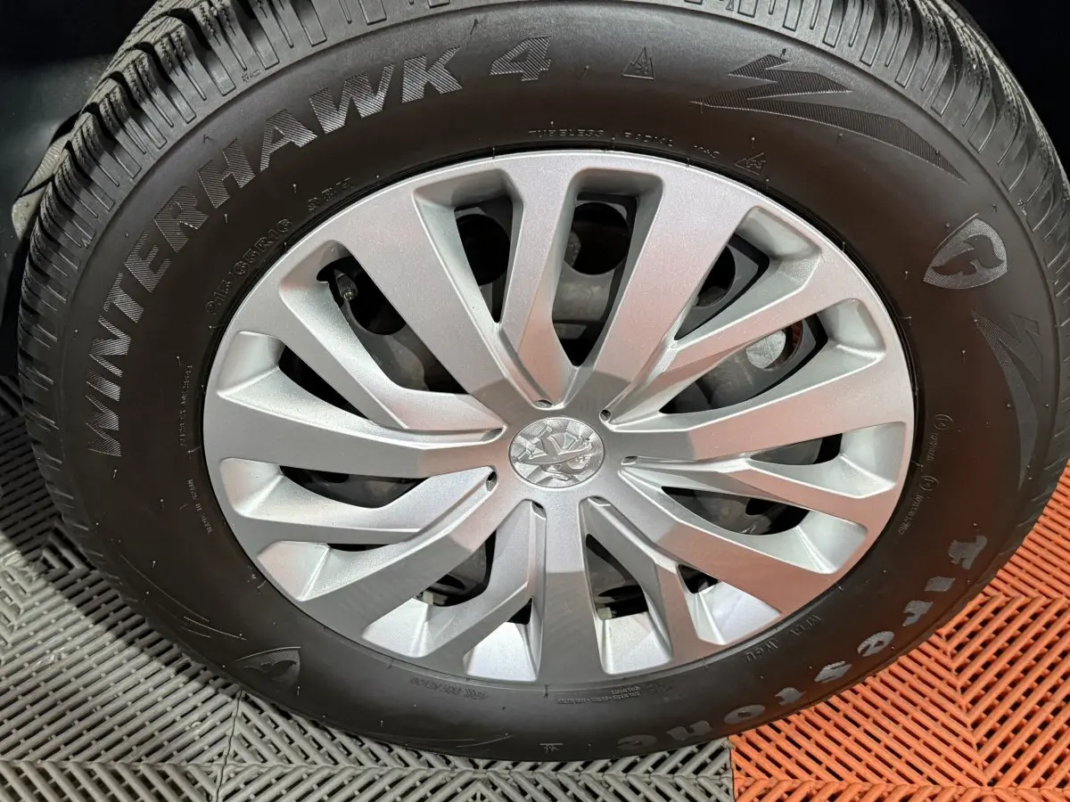 Gros plan sur la roue avant avec jante argentée et pneu Firestone Winterhawk 4 sur Peugeot Rifter blanc.