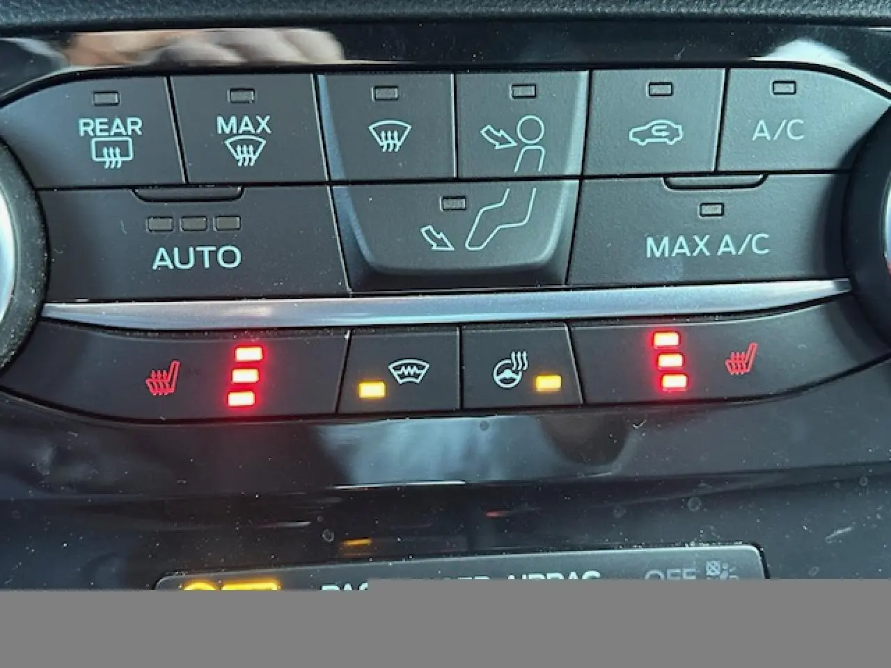 Gros plan sur les commandes de climatisation et sièges chauffants du Ford Puma gris Solar, avec voyants rouges allumés.