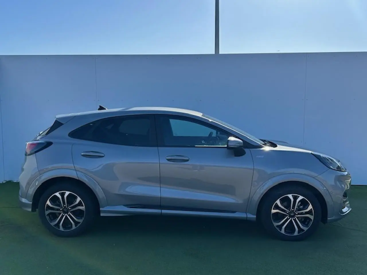 Profil droit du Ford Puma gris Solar 2023 avec jantes alliage et vitres surteintées, sur fond neutre.