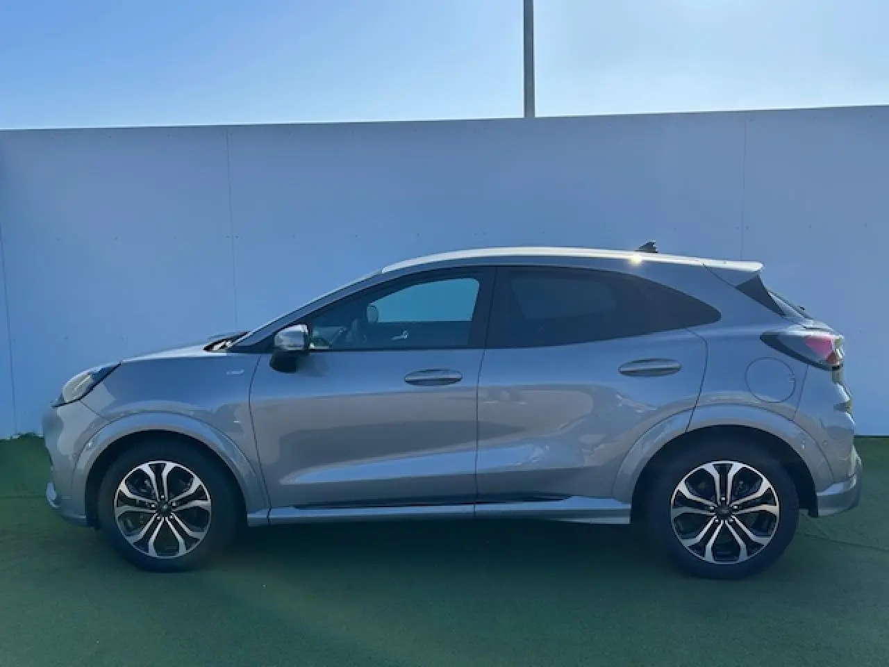 Profil côté gauche du Ford Puma gris Solar 2023 avec jantes alliage et vitres arrière surteintées.