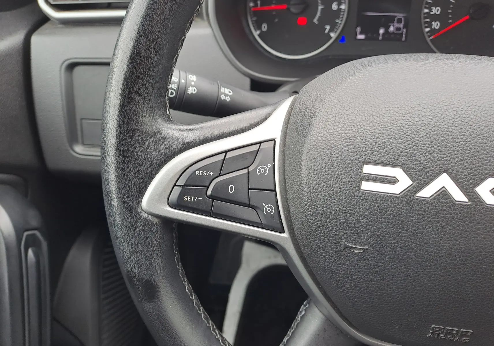 Gros plan sur le volant noir du Dacia Duster 2024, avec commandes de régulateur de vitesse visibles à gauche.