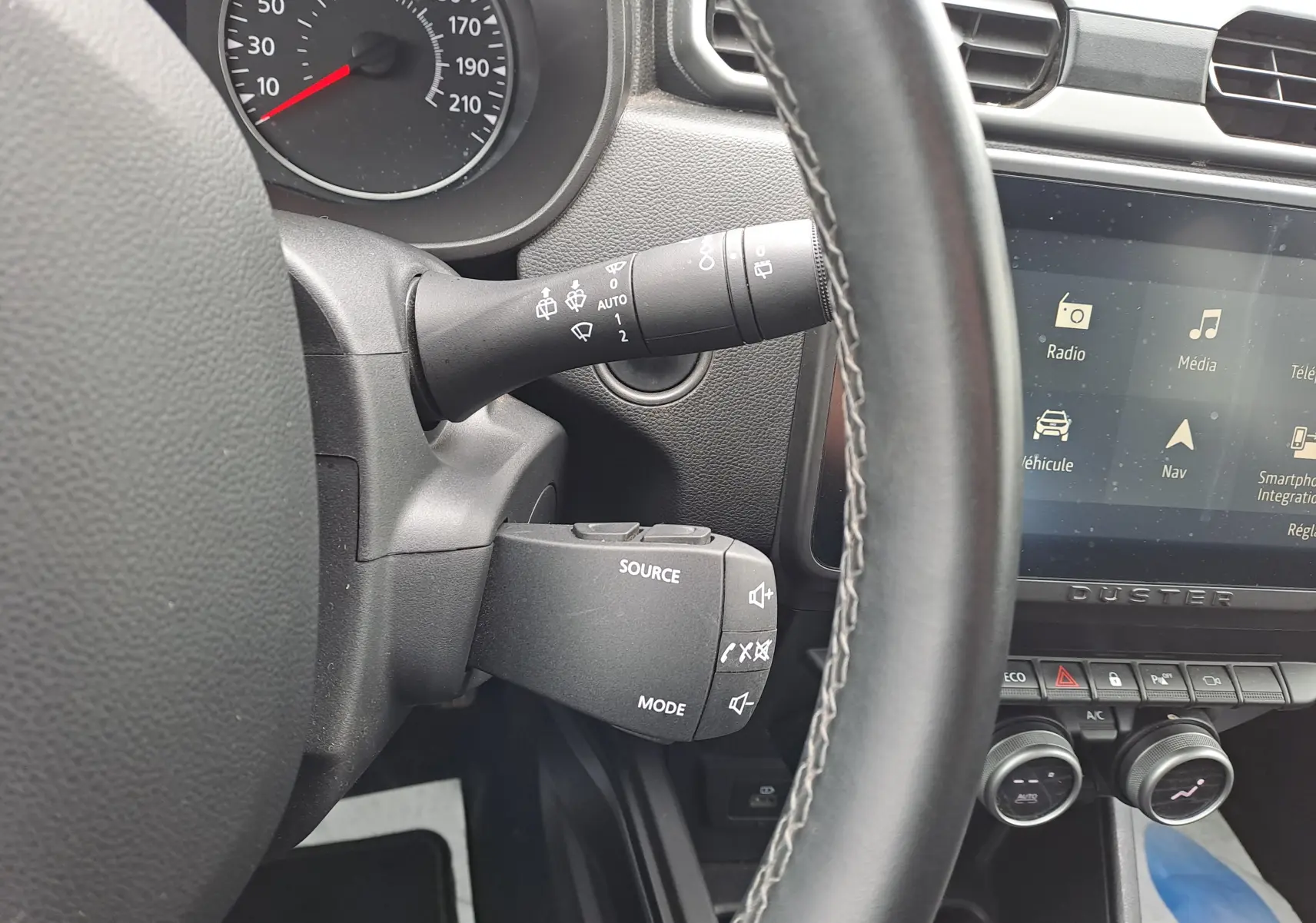 Vue rapprochée du volant et de la commande multimédia du Dacia Duster 2024 gris urbain, avec écran tactile et tableau de bord.