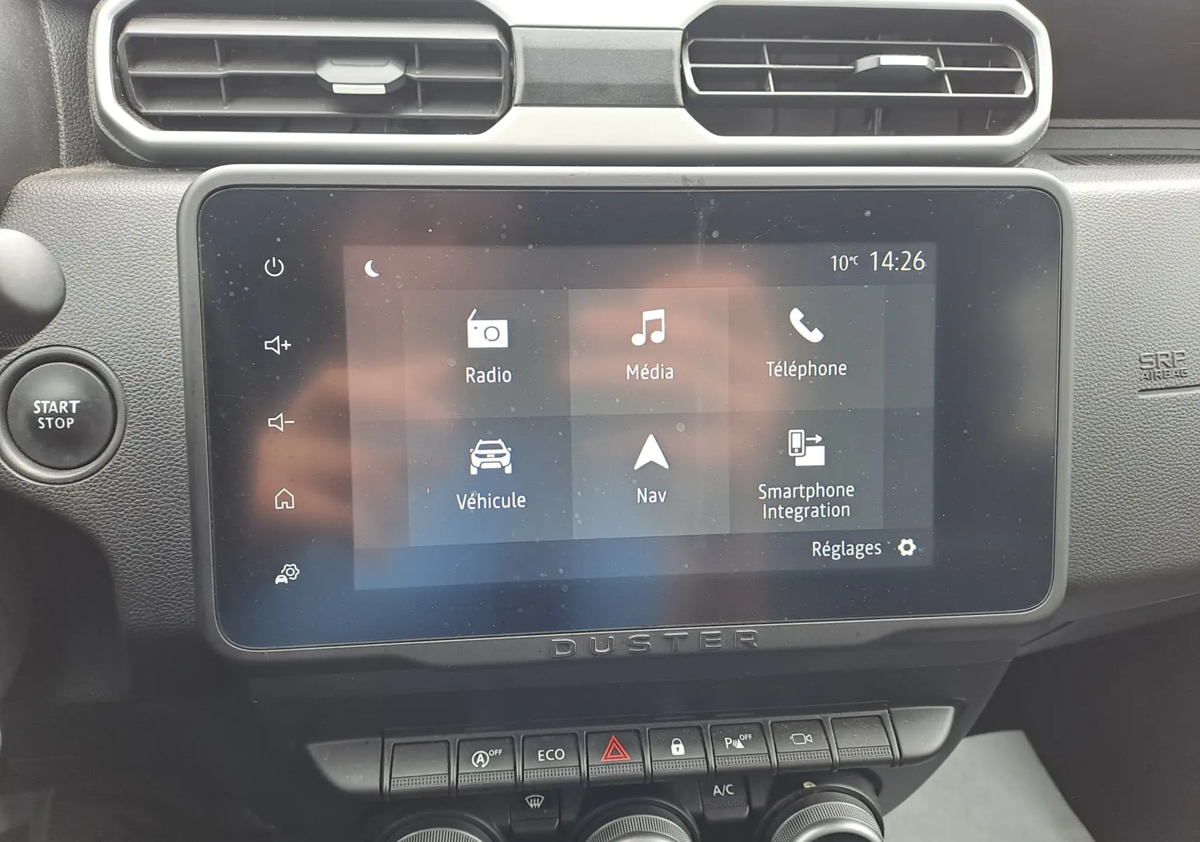 Vue rapprochée de l’écran tactile central du Dacia Duster gris urbain 2024 avec commandes et bouton Start/Stop.