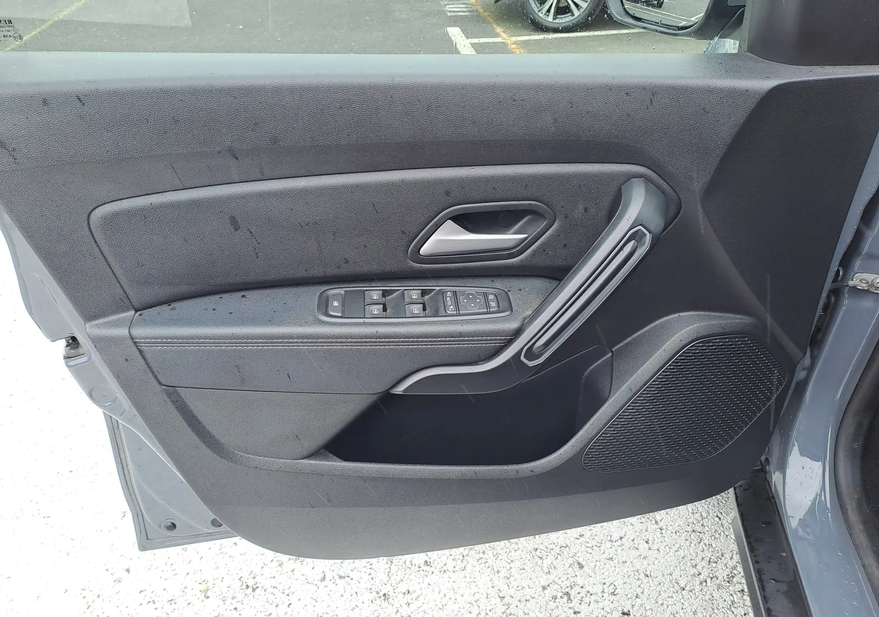 Vue rapprochée de la porte avant gauche gris urbain du Dacia Duster 2024 avec commandes électriques et poignée intégrée.