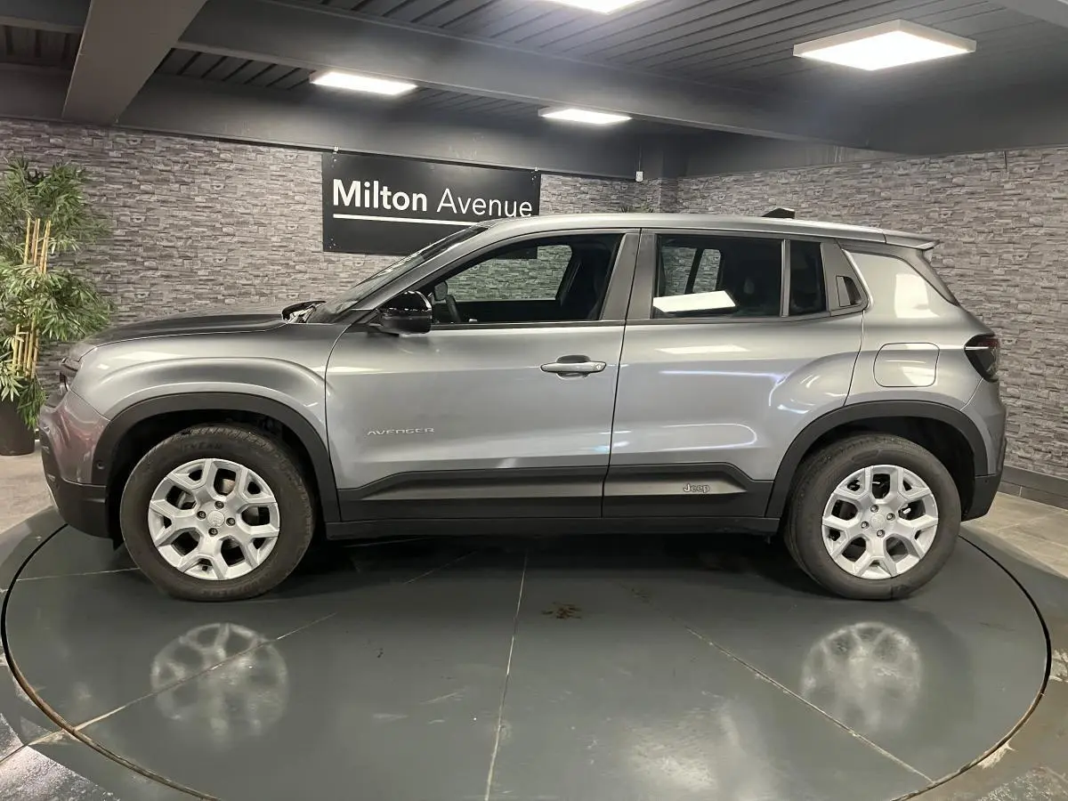 Vue de profil côté gauche d'un Jeep Avenger gris métallisé avec jantes alliage et coques de rétroviseurs noires.