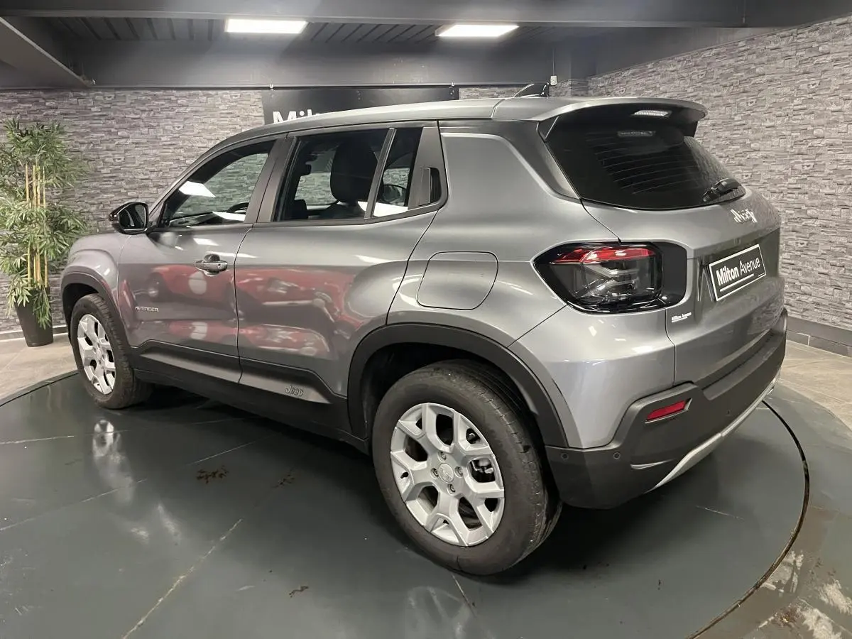 Vue 3/4 arrière droite du Jeep Avenger gris métallisé avec jantes alliage et coques de rétroviseurs noires.