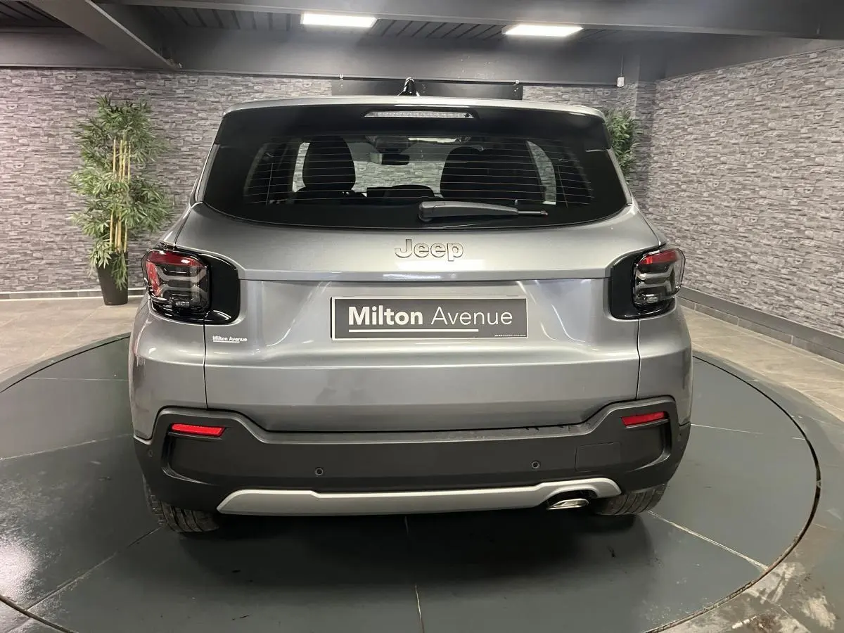 Vue arrière du Jeep Avenger gris métallisé avec feux arrière noirs et logo Jeep visible en intérieur.