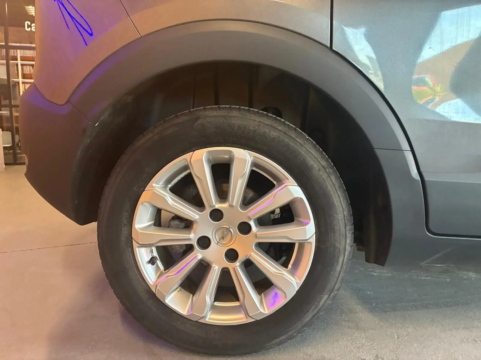 Gros plan sur la roue arrière droite d’un Opel Crossland gris 2021 avec jante alliage et pneumatique Bridgestone.