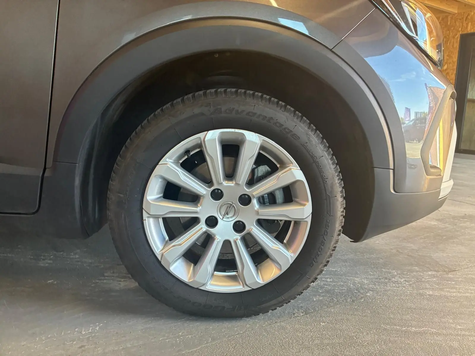 Gros plan sur la roue avant droite gris argenté d’un Opel Crossland gris, avec jante alu et partie avant du véhicule visible.