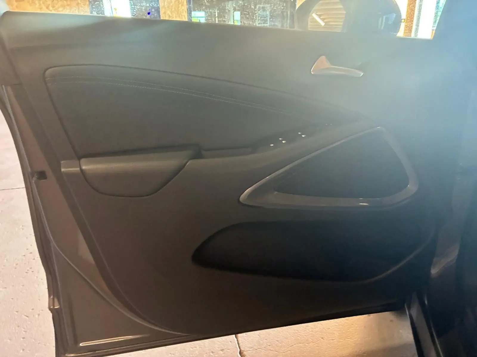 Vue intérieure de la porte côté gauche d'une Opel Crossland gris, mettant en valeur les commandes de fenêtre et la poignée argentée.