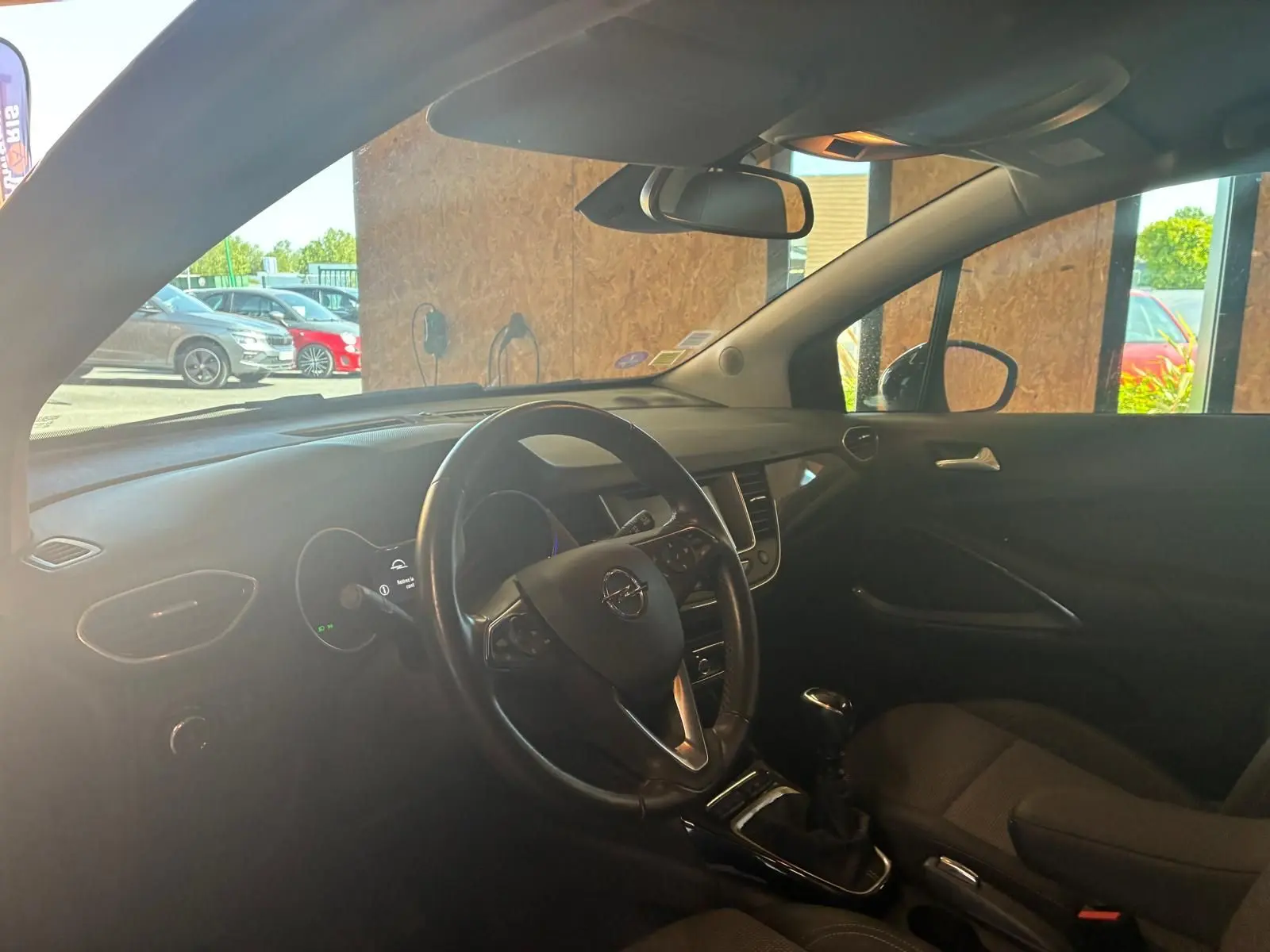 Vue intérieure côté conducteur de l'Opel Crossland gris, montrant le volant multifonction et la console centrale avec boîte manuelle.