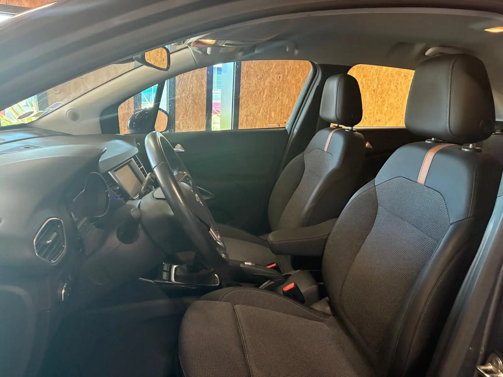 Vue intérieure côté conducteur de l’Opel Crossland gris, mettant en valeur les sièges tissu gris-noir avec bande centrale marron.