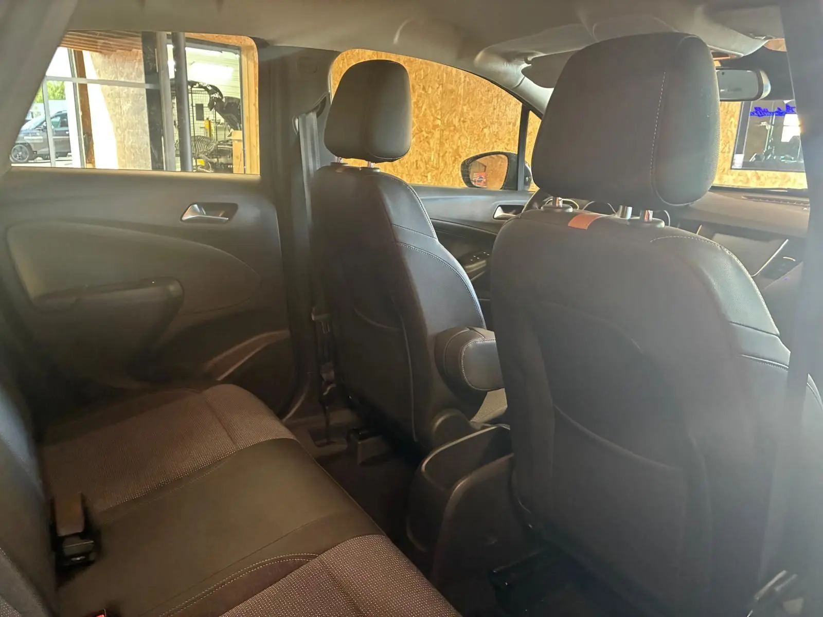 Vue intérieure arrière de l’Opel Crossland 2021, sièges tissu gris et noir avec appuie-bras central déployé.