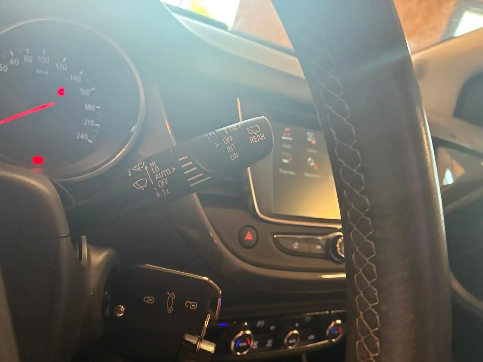 Gros plan sur la commande d’essuie-glace à gauche du volant d’un Opel Crossland gris, tableau de bord et écran tactile en arrière-plan.