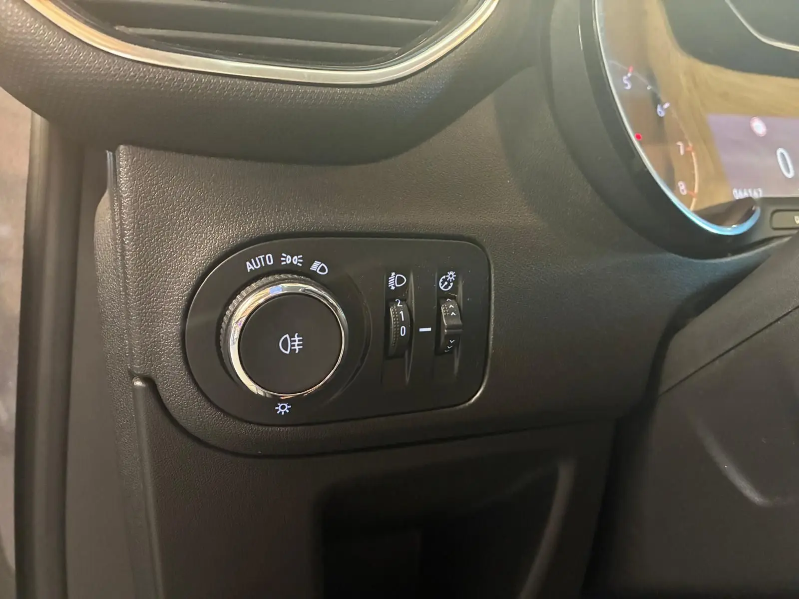 Gros plan sur le panneau de commande des phares à gauche du tableau de bord d’un Opel Crossland gris 2021.