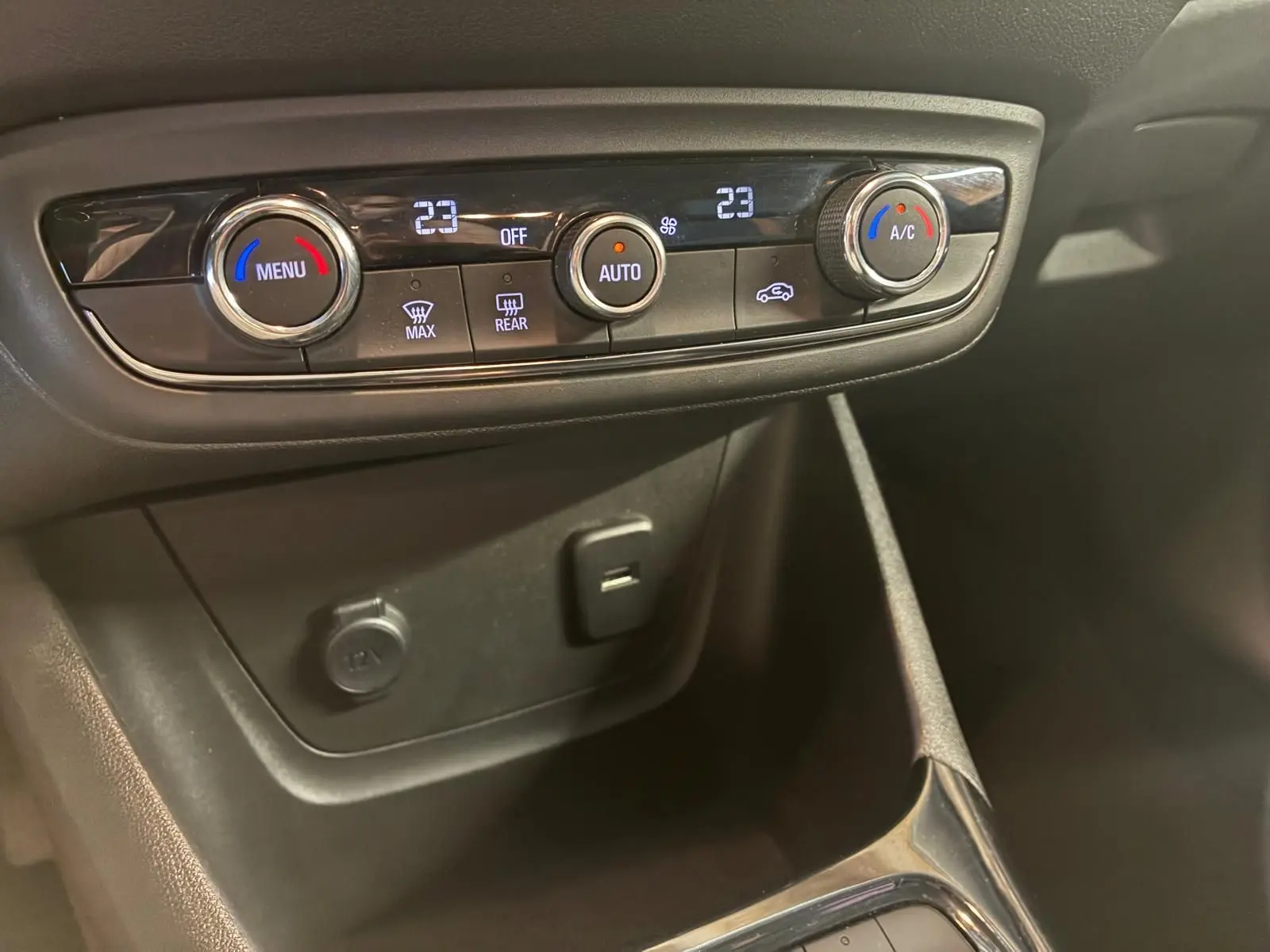 Vue rapprochée de la commande de climatisation digitale et des prises USB et 12V de l’Opel Crossland gris 2021.