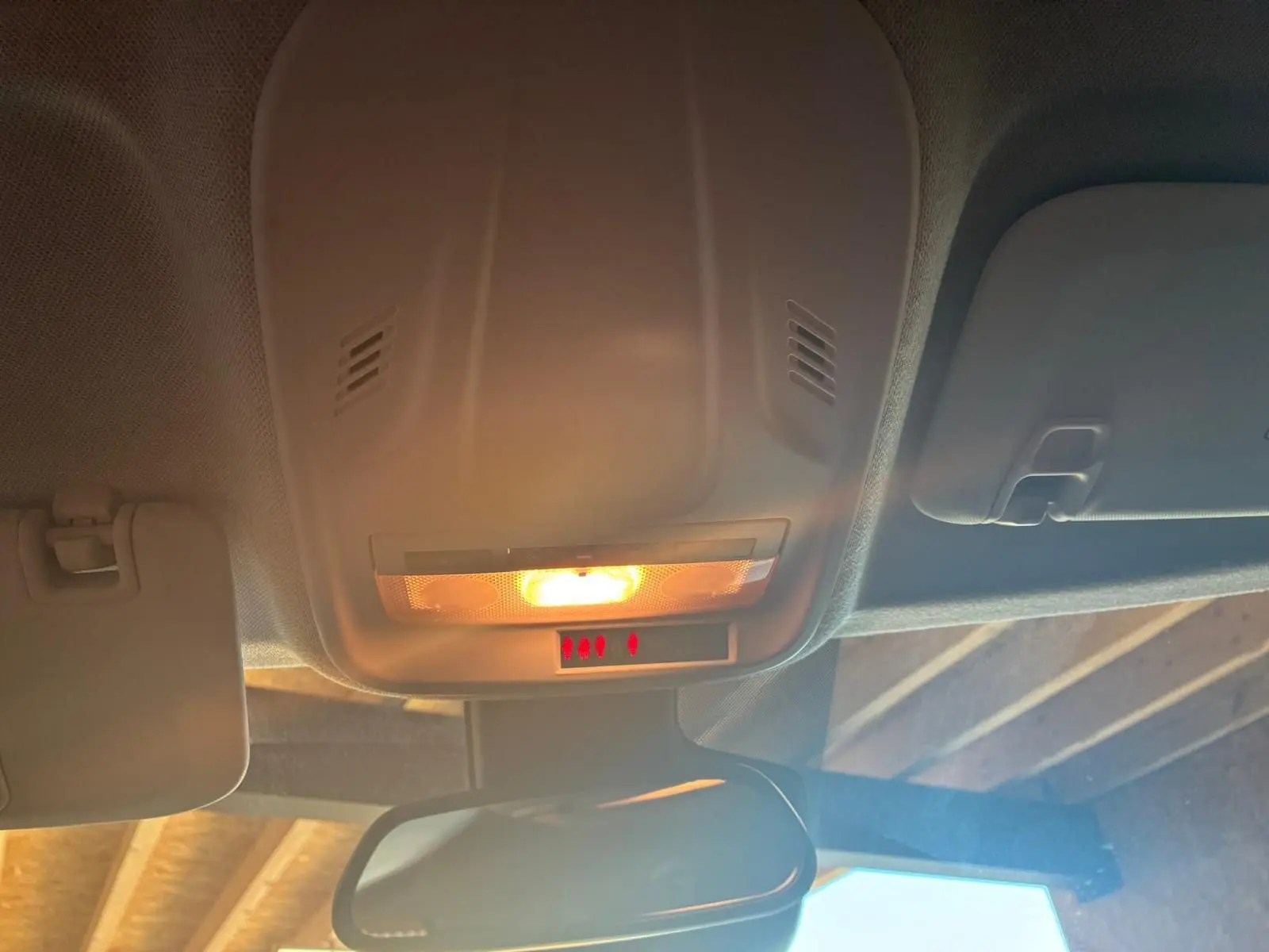 Plafonnier intérieur allumé avec miroir de courtoisie et pare-soleil dans un Opel Crossland gris, vue de l'habitacle vers l'avant.