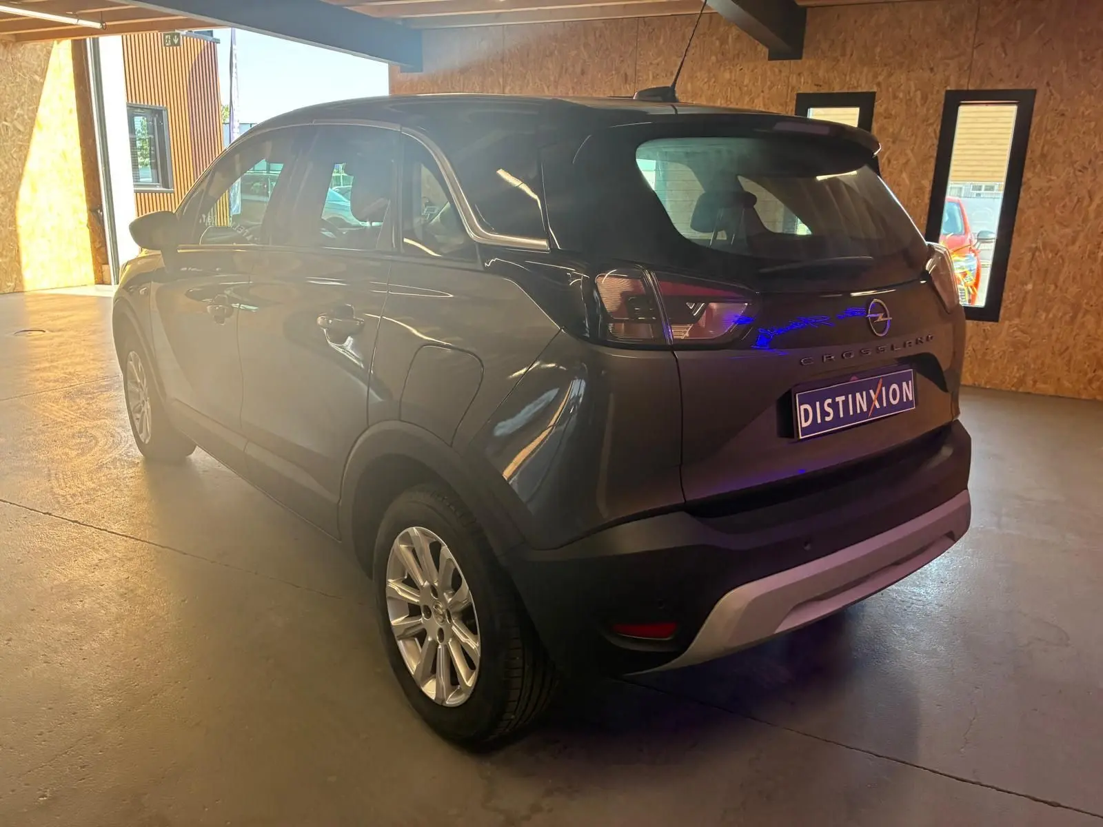 Vue 3/4 arrière droite d'un Opel Crossland gris 2021 avec feux arrière LED et jantes alliage en intérieur lumineux.