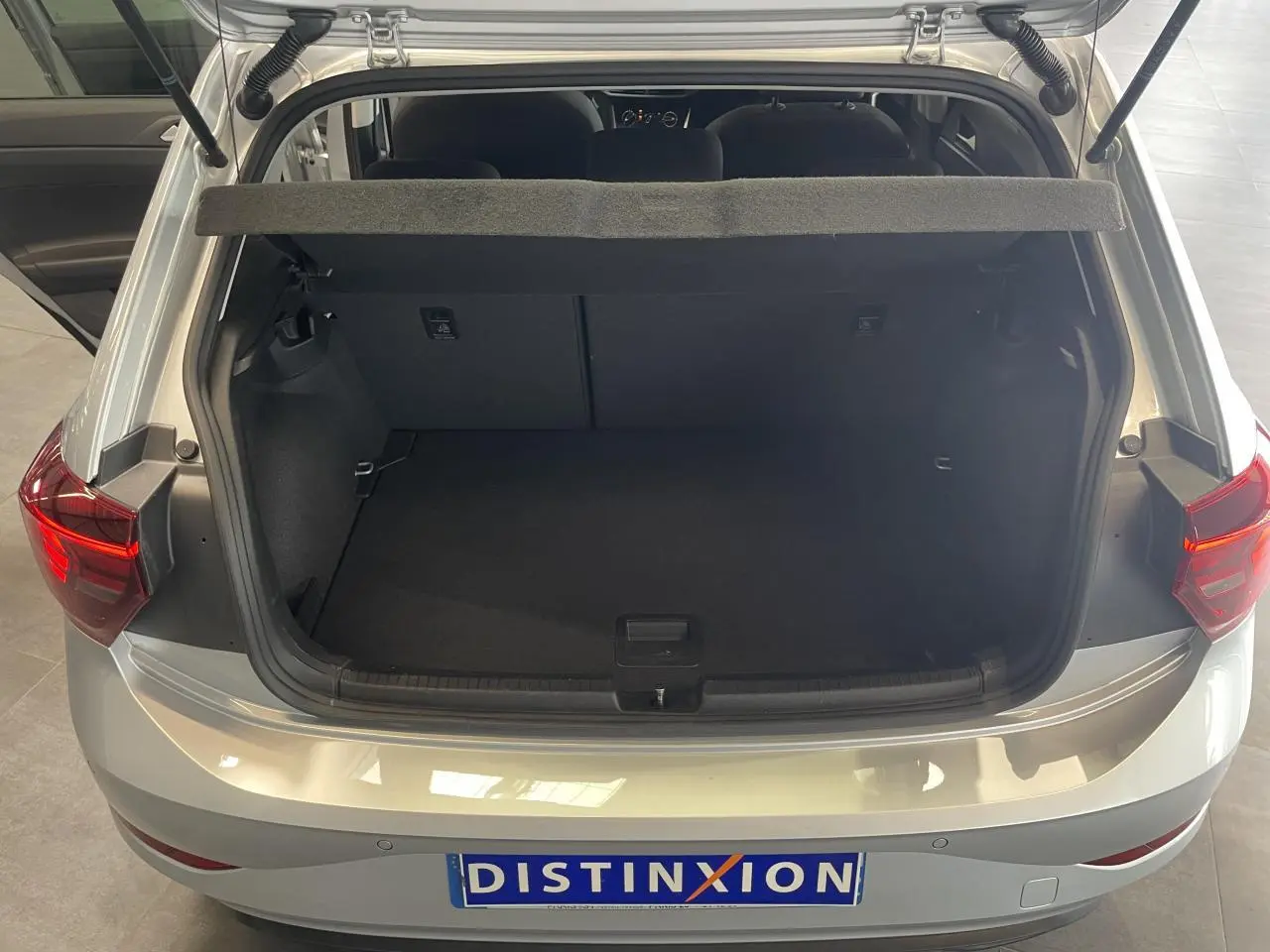 Vue arrière ouverte sur le coffre spacieux d'une Volkswagen Polo gris clair 2024 avec feux arrière allumés.