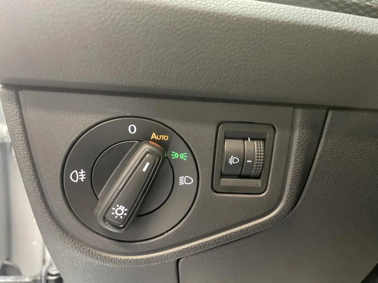 Gros plan sur le bouton de commande des phares d’un Volkswagen Polo gris clair, intérieur côté conducteur.