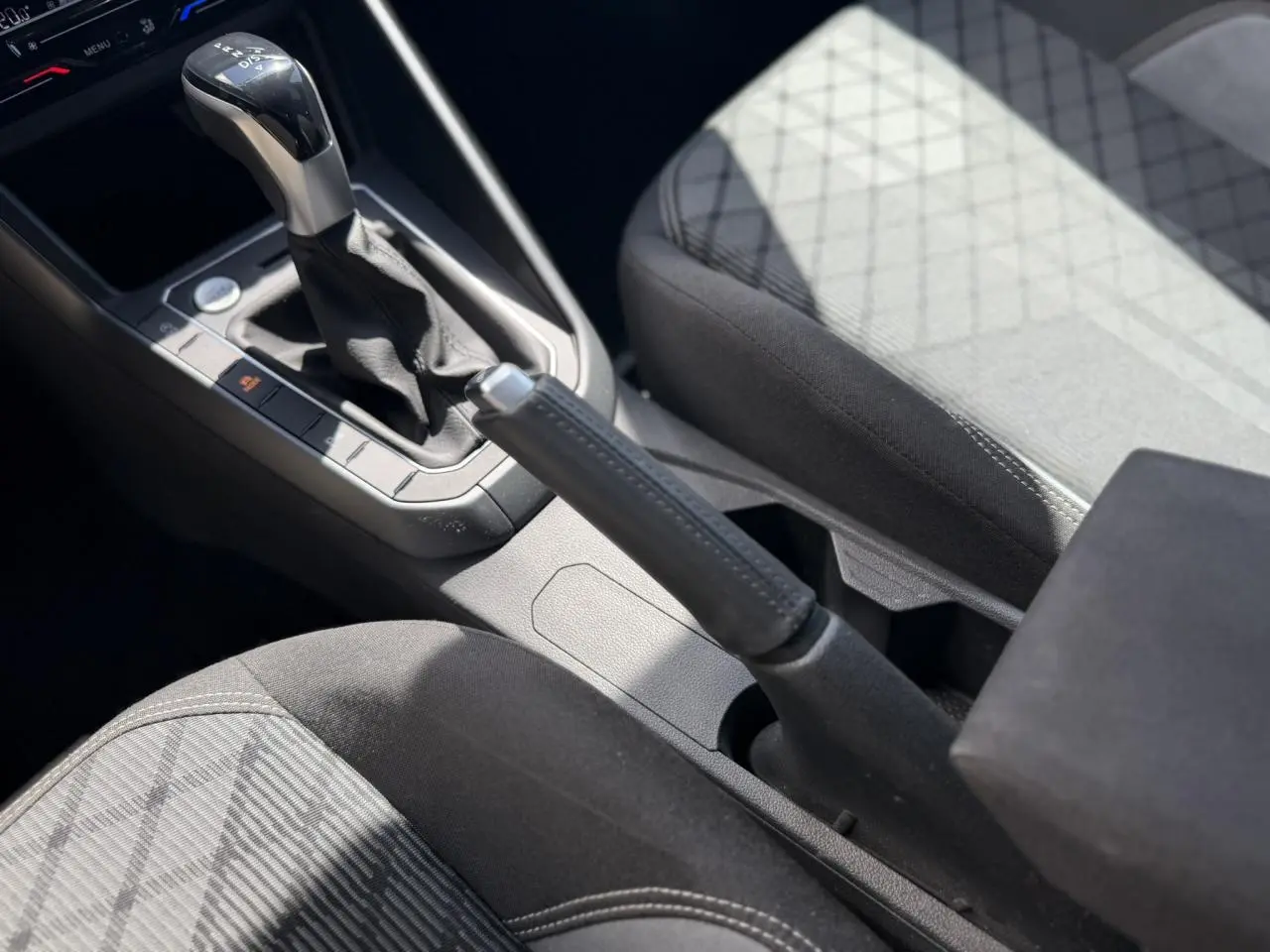 Vue rapprochée de la console centrale du Volkswagen Taigo 2025, montrant levier de vitesses DSG et frein à main manuel.
