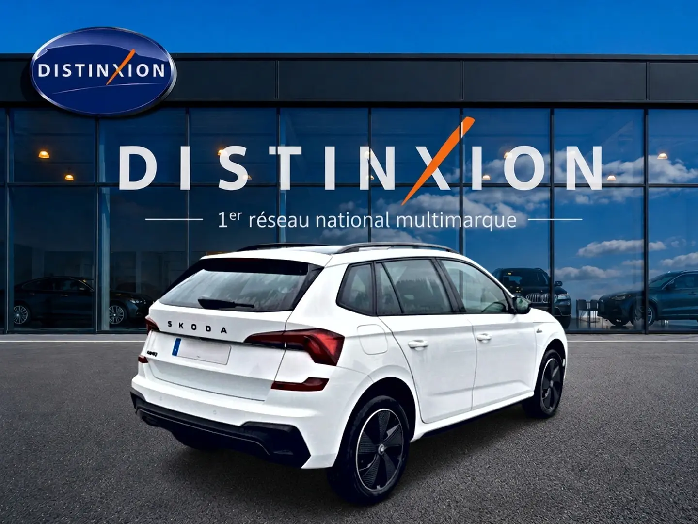 SKODA KAMIQ blanc nacré vu en 3/4 arrière droit devant un showroom Distinxion.