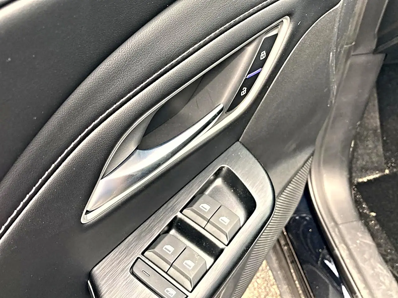 Détail de la porte avant gauche du MG ZS noir, avec commandes électriques des vitres et poignée argentée.