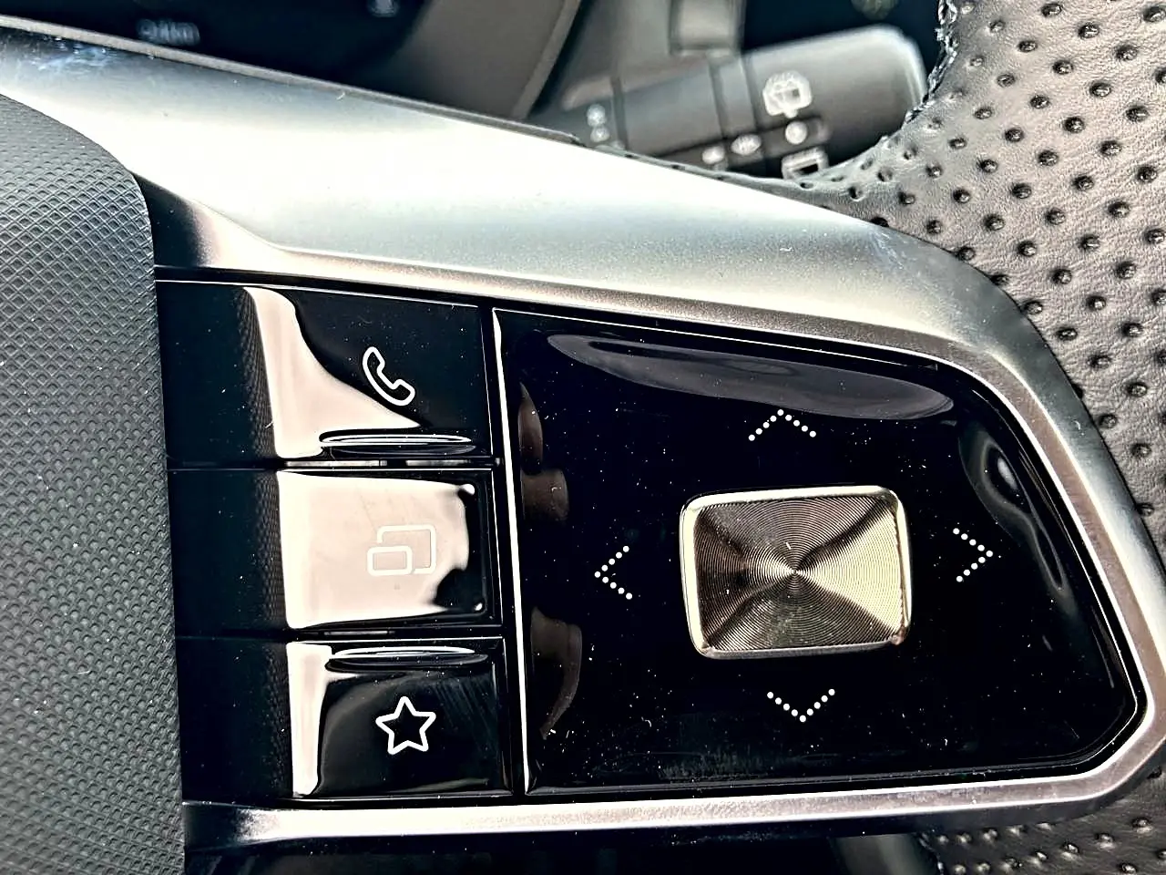 Gros plan sur les commandes noires et argentées du volant perforé du MG Motor ZS 1.5 hybrid 197 luxury noir.