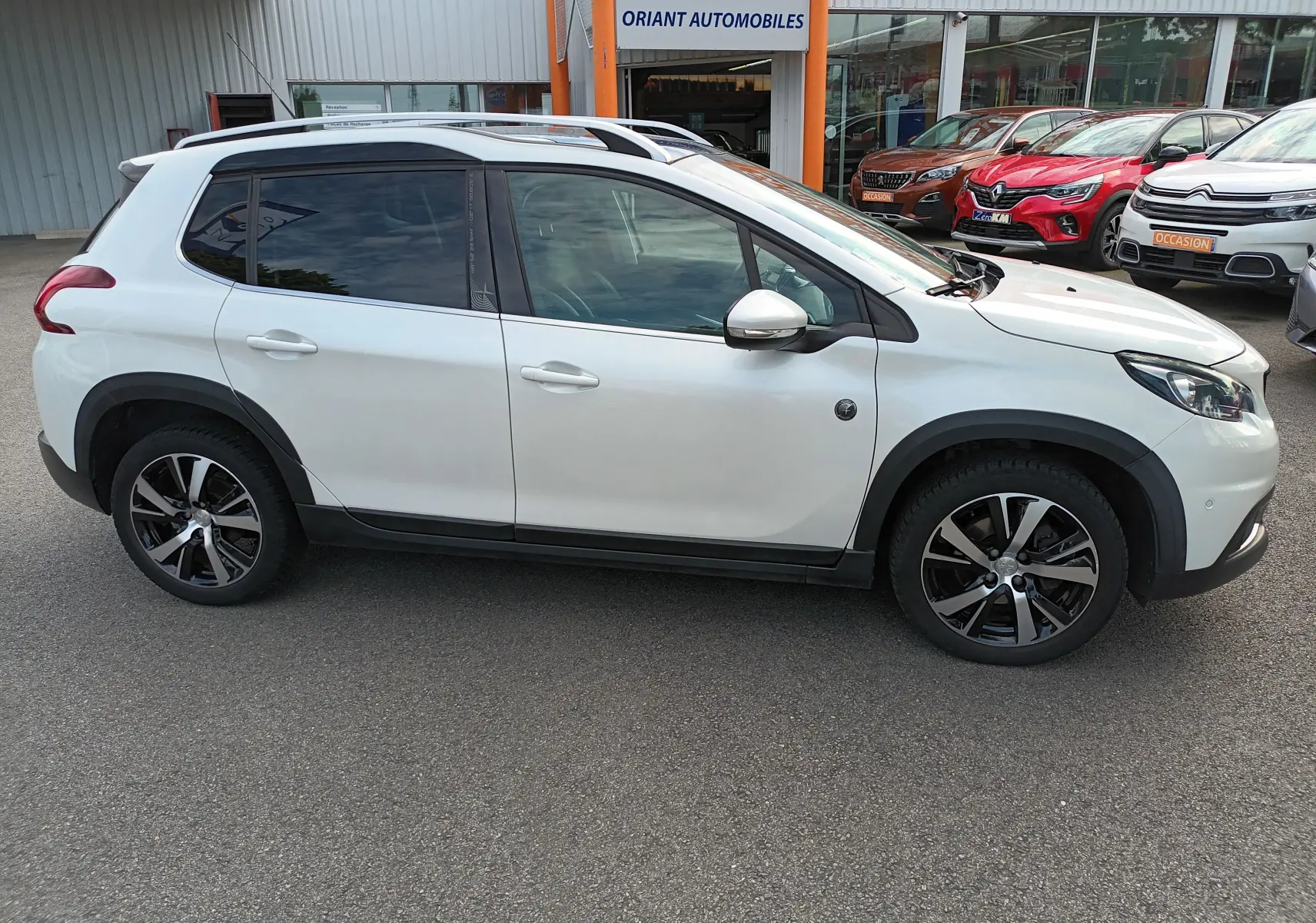 Profil droit d'un Peugeot 2008 blanc 2018 version PureTech 130 Crossway avec jantes alliage et barres de toit.