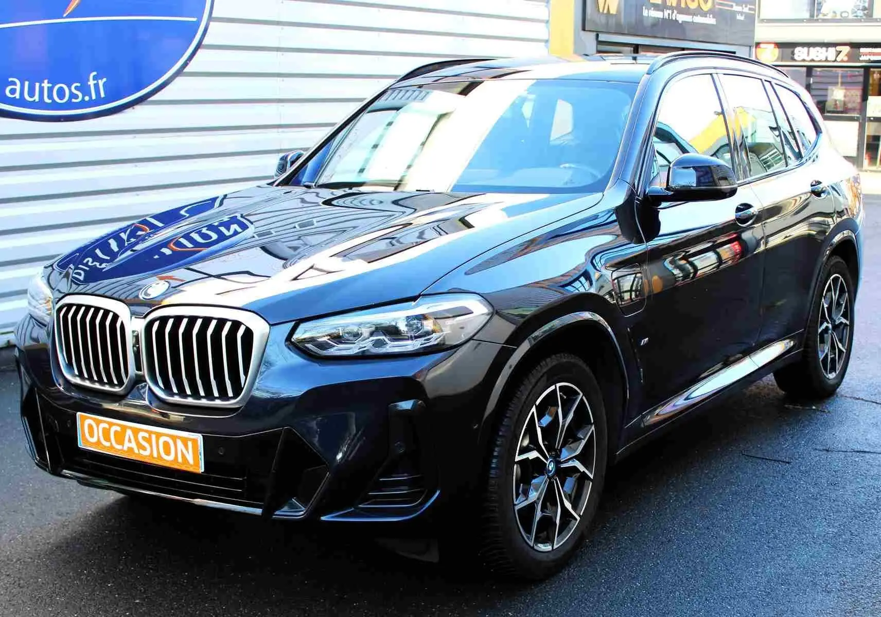 BMW X3 xDrive 30e bleu métal vu en 3/4 avant droit, avec calandre imposante et jantes M Sport distinctives.