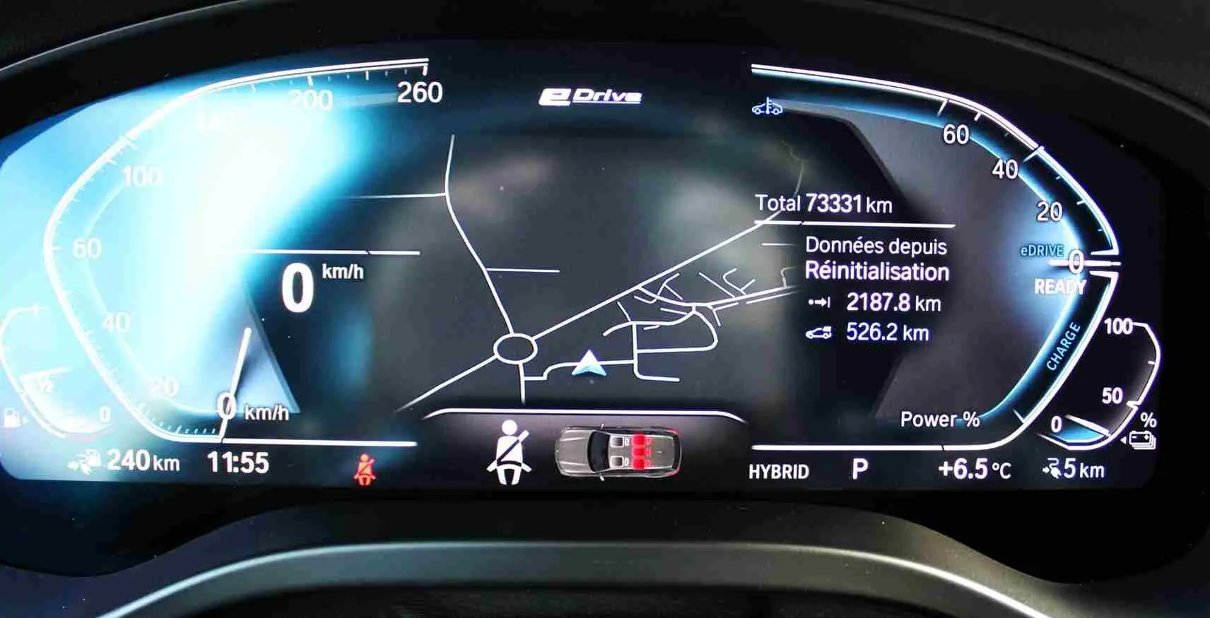 Tableau de bord numérique du BMW X3 xDrive 30e 2023 affichant la vitesse, la carte de navigation et l'état hybride rechargeable.