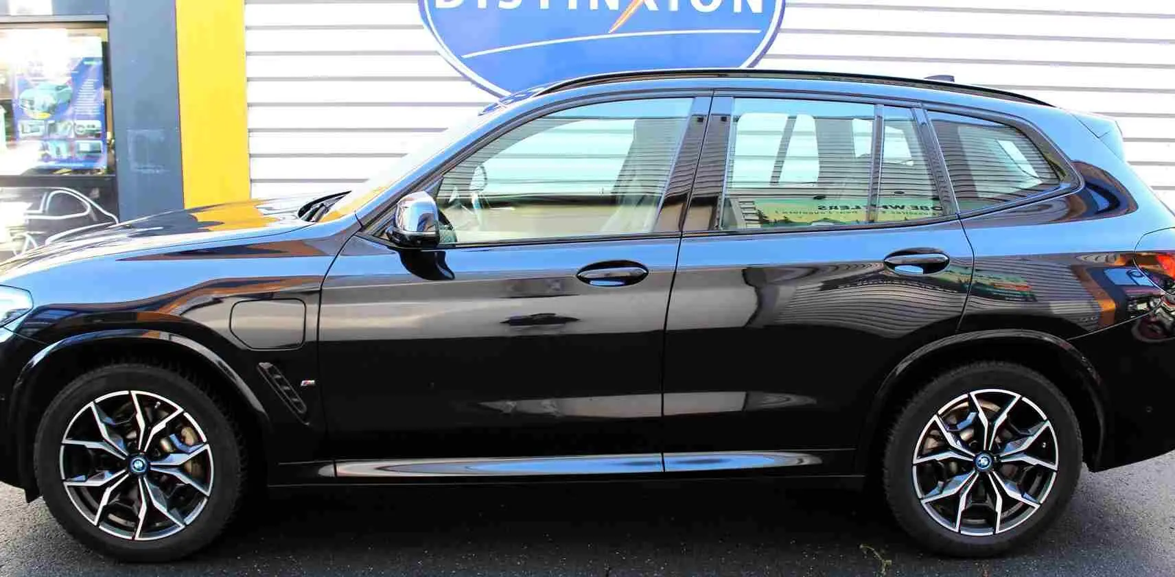 Profil côté gauche d'un BMW X3 xDrive 30e 2023 en bleu métal avec jantes alliage et badge M Sport visible.