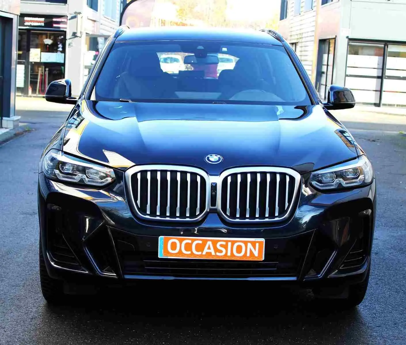 Vue frontale d'un BMW X3 xDrive bleu métal 2023 avec calandre imposante et plaque "OCCASION" orange.