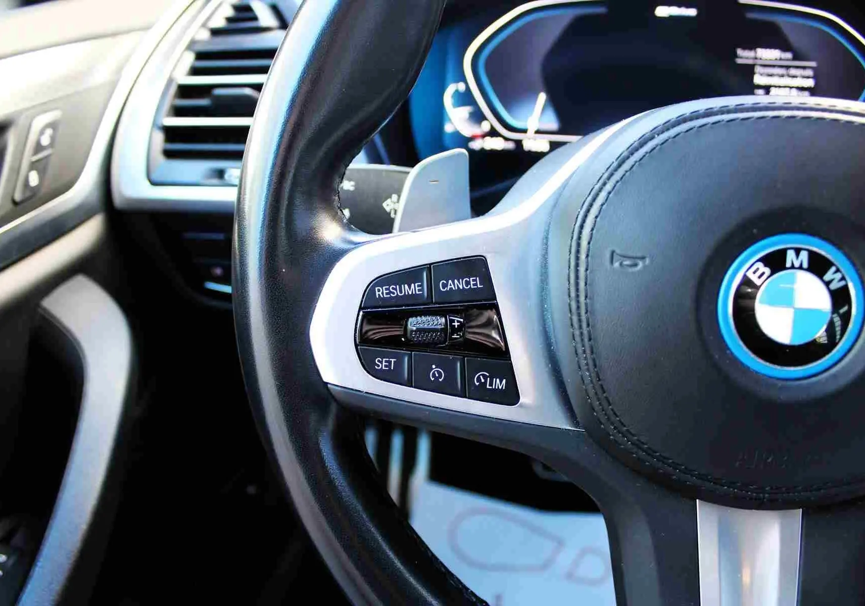 Gros plan sur le volant cuir noir avec commandes de régulateur sur la BMW X3 xDrive hybride rechargeable 2023.