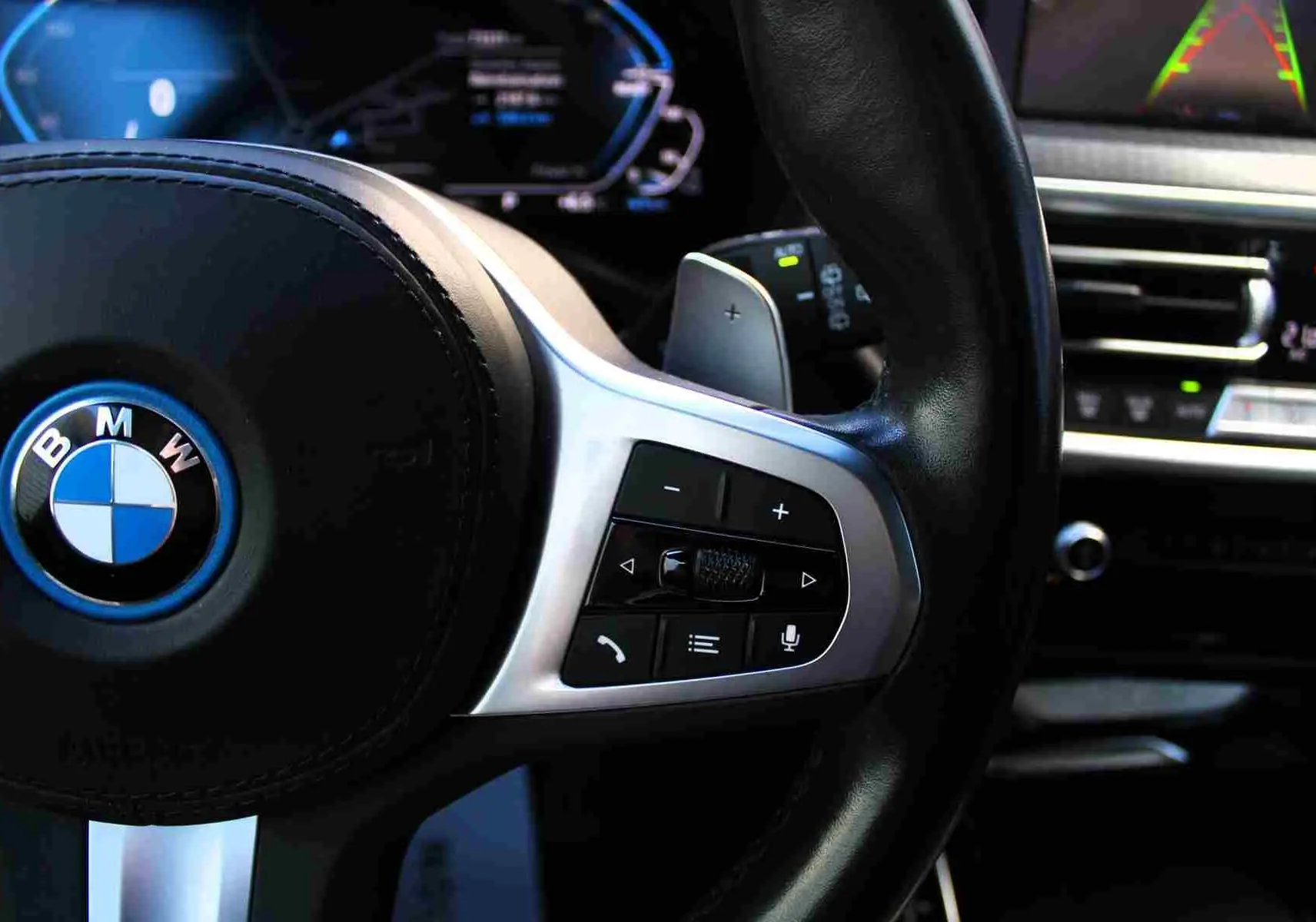 Gros plan sur le volant multifonction noir avec logo BMW bleu du BMW X3 xDrive 30e 2023 hybride rechargeable.