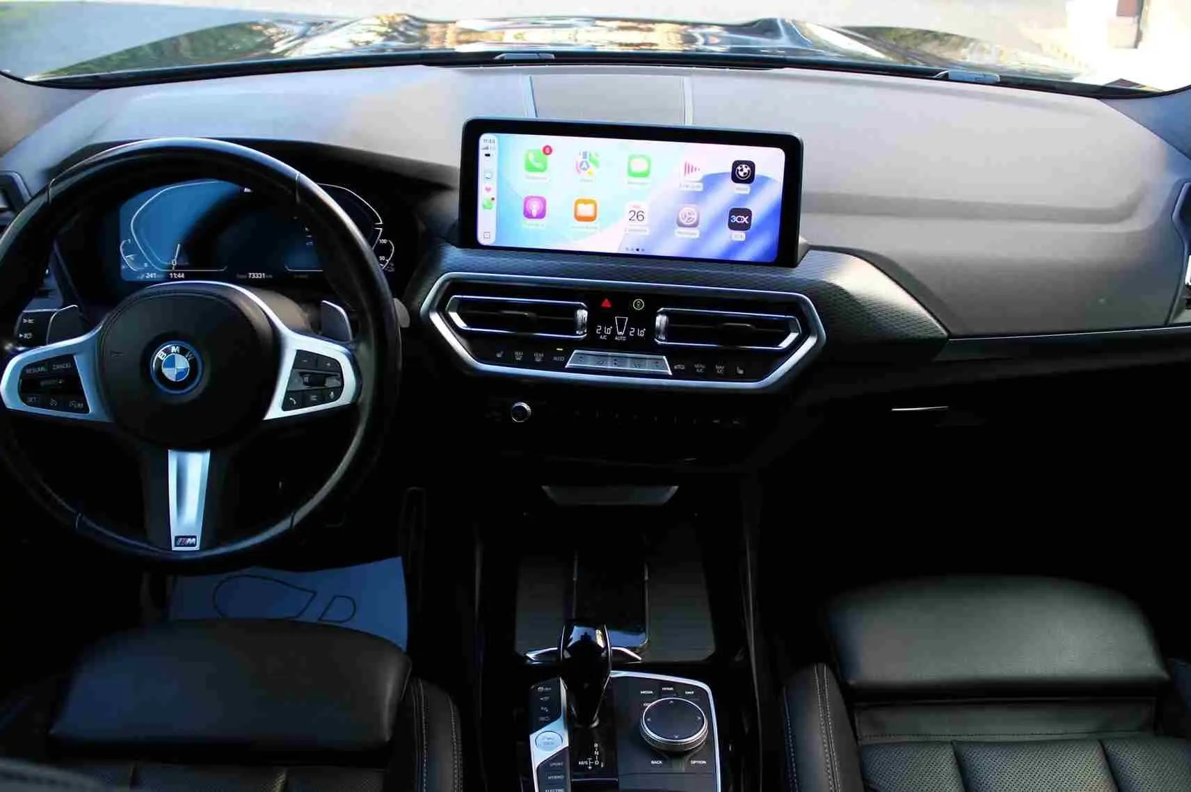 Vue intérieure frontale du tableau de bord du BMW X3 xDrive 30e 2023 avec écran tactile et volant M Sport noir.