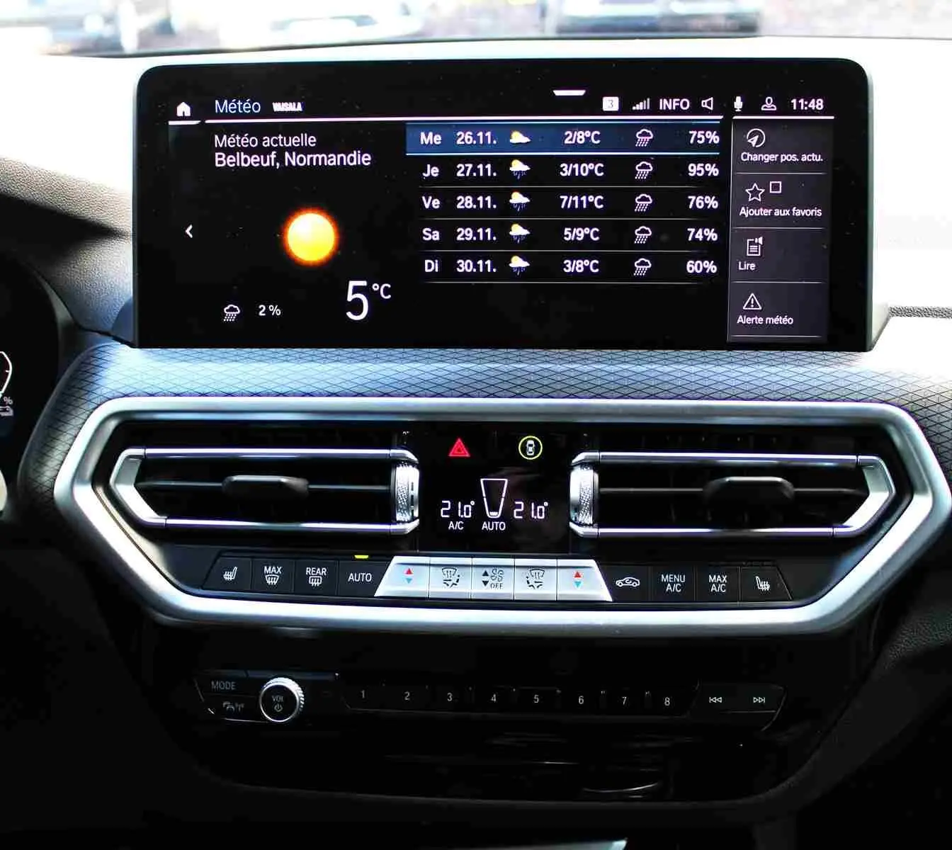 Écran tactile central affichant la météo dans l'habitacle du BMW X3 xDrive bleu métal, version hybride rechargeable 2023.