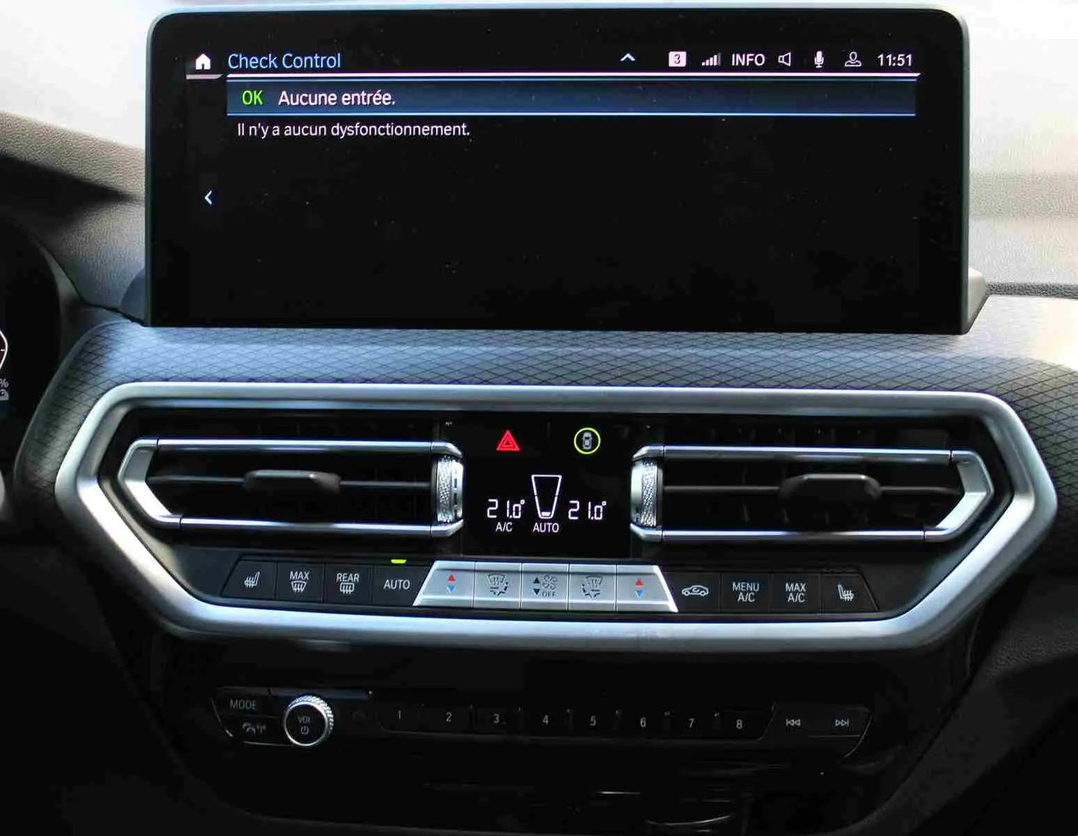 Vue rapprochée du tableau de bord du BMW X3 xDrive 30e 2023 bleu métal, affichant l'écran central et commandes climatisation.