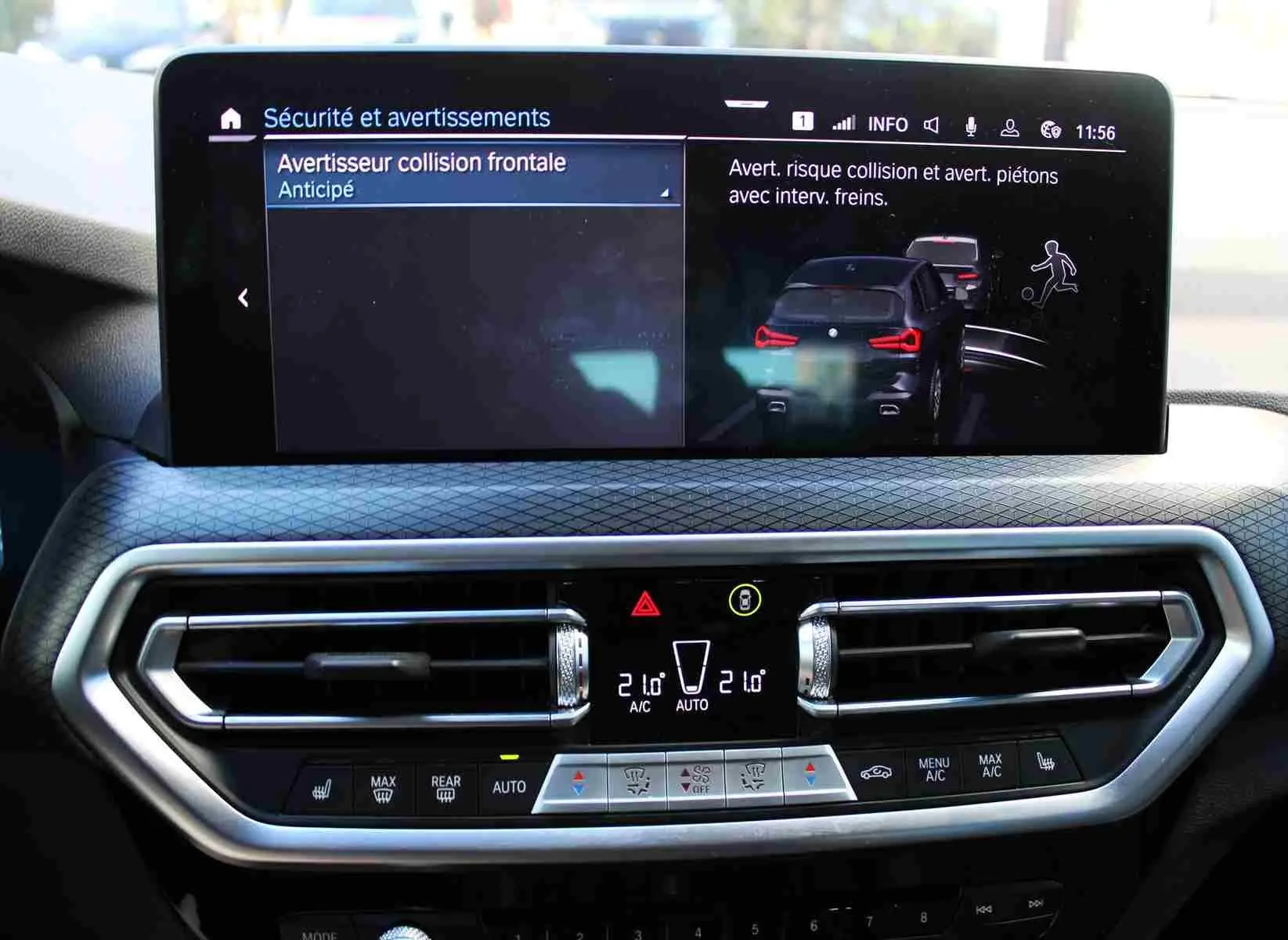 Tableau de bord du BMW X3 xDrive 30e 2023 avec écran tactile affichant l'alerte collision et commandes climatisation intégrées.