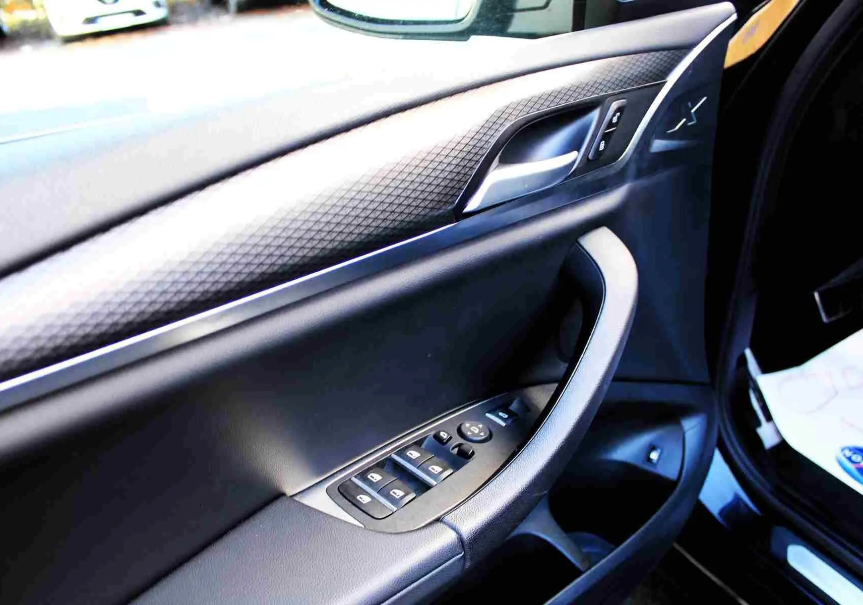 Détail de la porte côté conducteur du BMW X3 xDrive 30e 2023 bleu métal avec commandes de vitres et insert décoratif.