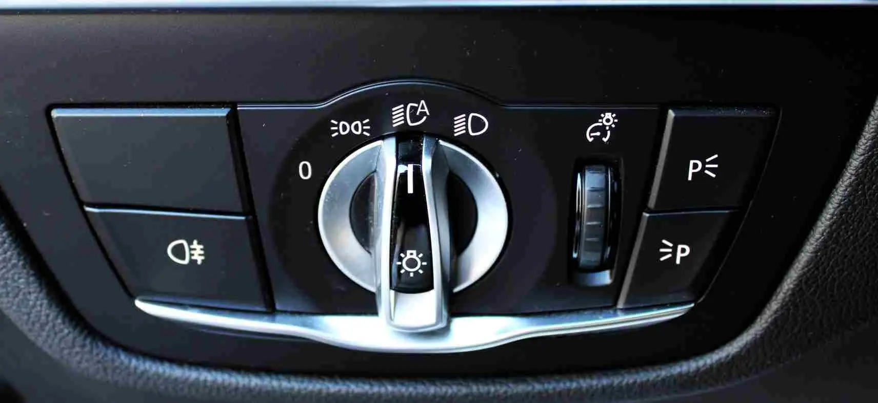 Commande des feux avec molette argentée et boutons noirs dans l'habitacle du BMW X3 xDrive bleu métal 2023