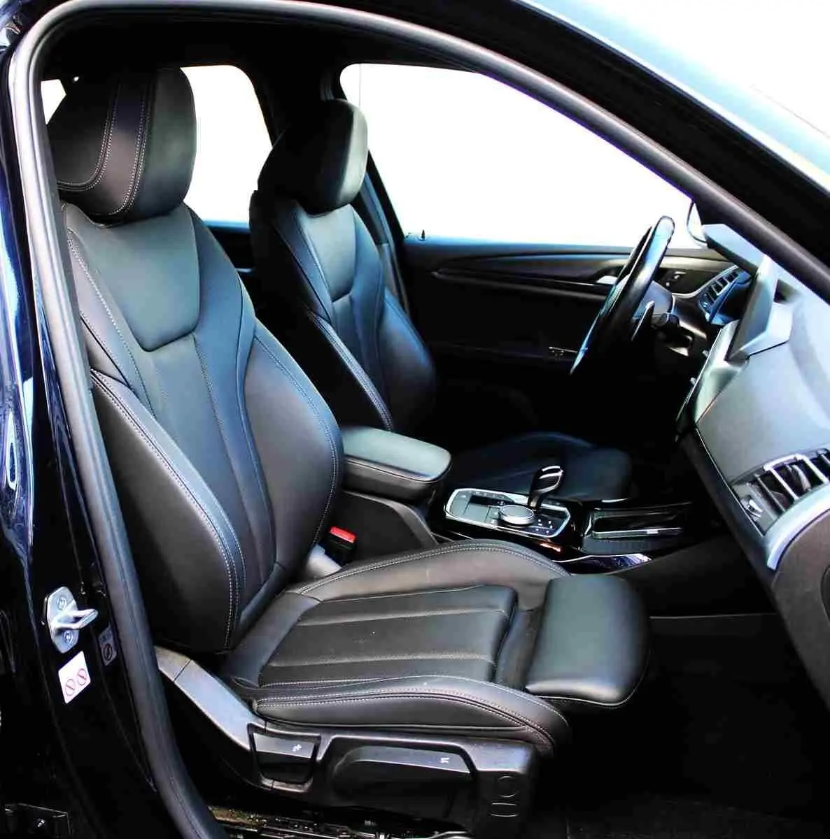 Intérieur côté conducteur du BMW X3 xDrive 30e 2023 avec sièges cuir noirs et console centrale moderne.