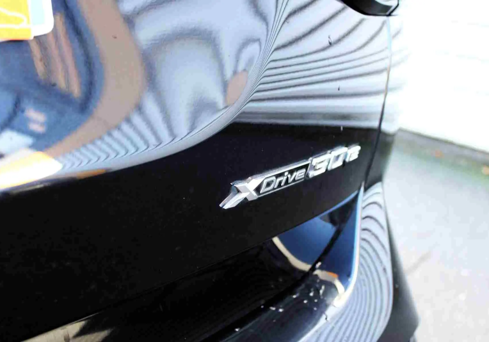 Gros plan sur l'emblème XDrive 30e sur l'aile arrière droite d'un BMW X3 bleu métal 2023 hybride rechargeable.