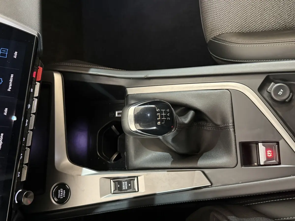 Vue rapprochée de la console centrale de la Peugeot 308 bleu, avec levier de vitesse manuel et bouton démarrage.