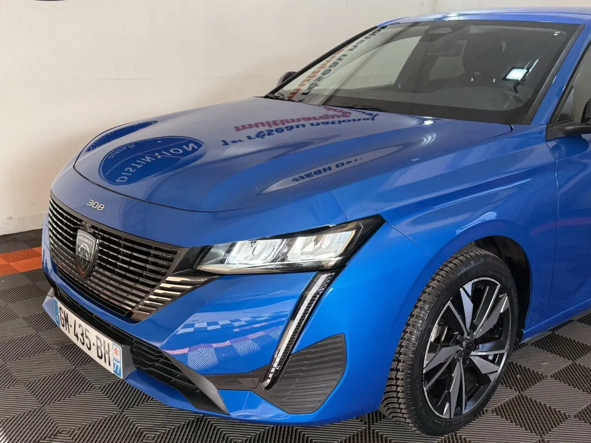 Vue 3/4 avant droit d'une Peugeot 308 2023 bleu électrique avec phares LED et jantes alliage distinctives.