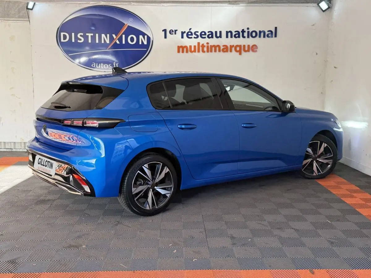 Peugeot 308 PureTech 130 S&S Allure Pack bleu vue 3/4 arrière droit en intérieur showroom.