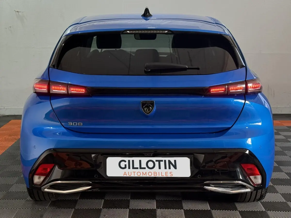 Vue arrière d’une Peugeot 308 bleu 2023 avec feux LED allumés et double sortie d’échappement chromée.