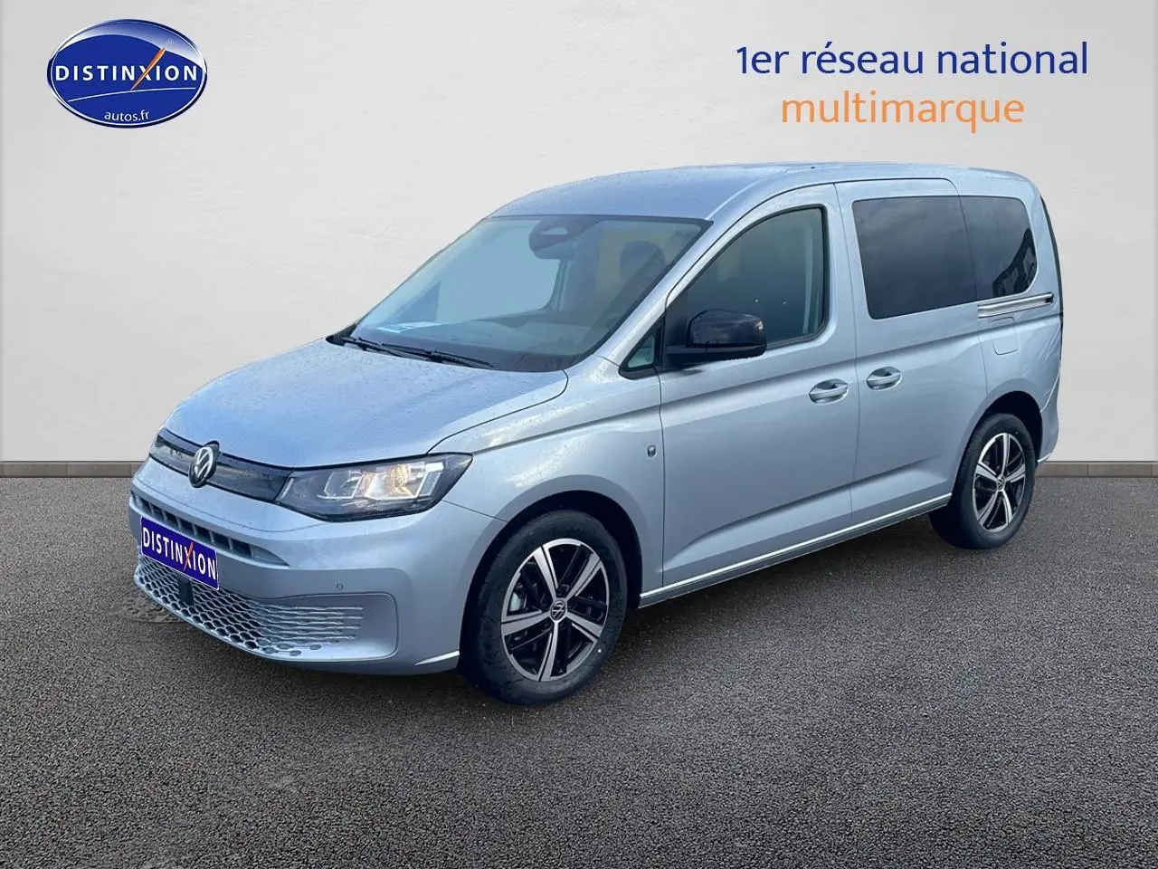 Volkswagen Caddy gris argent vu en 3/4 avant droit, avec jantes alliage et vitres arrière teintées.