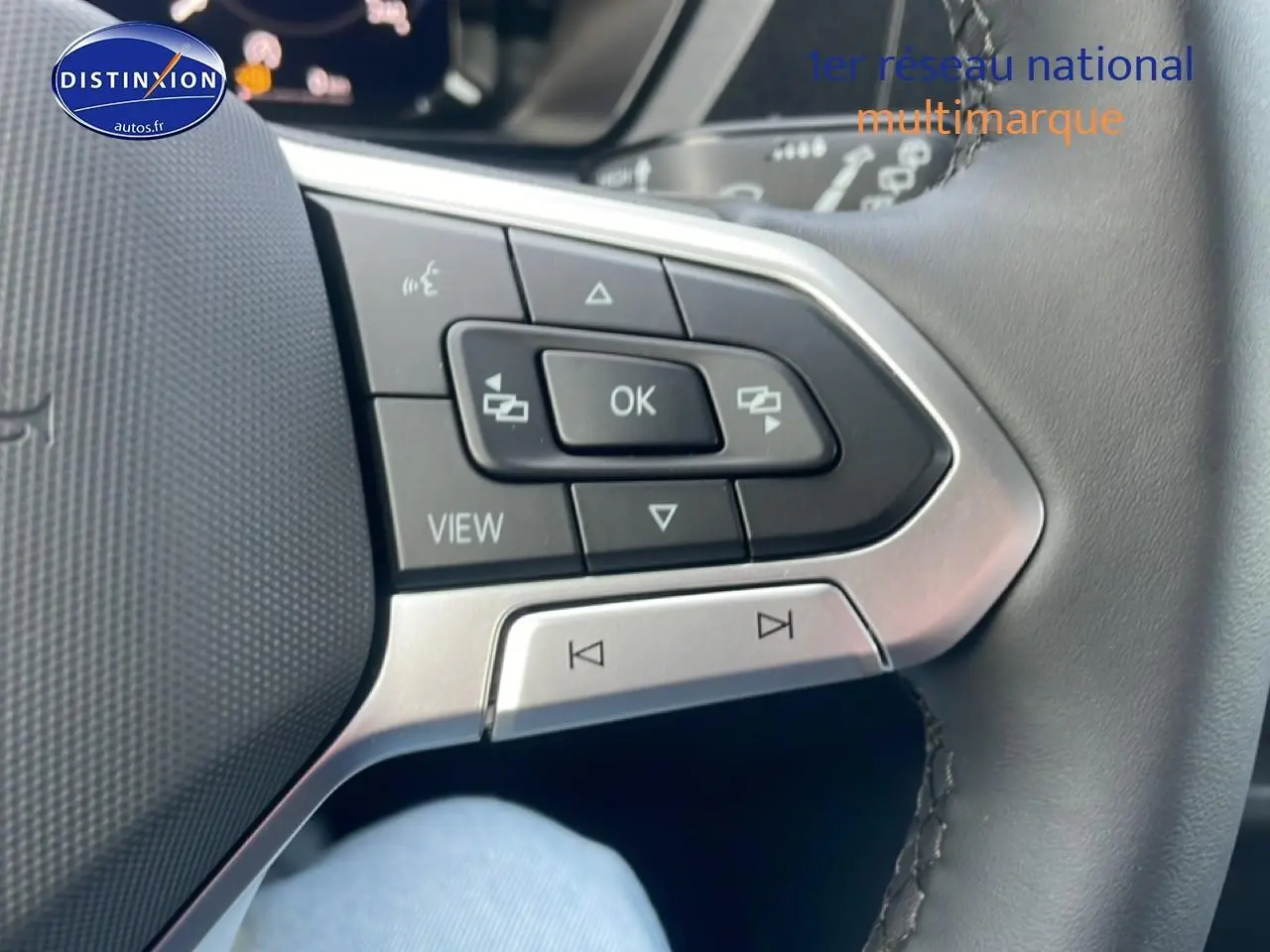 Gros plan sur les commandes multifonctions en cuir du volant côté gauche du Volkswagen Caddy gris argent 2025.