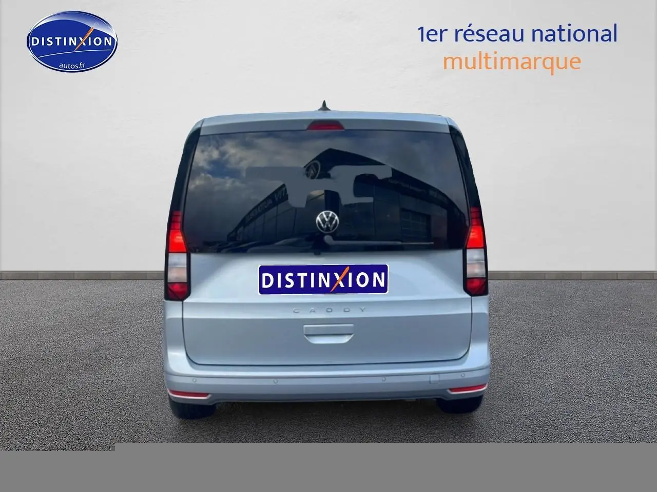 Vue arrière d'un Volkswagen Caddy gris argent 2025 avec vitres arrière teintées et feux rouges verticaux.